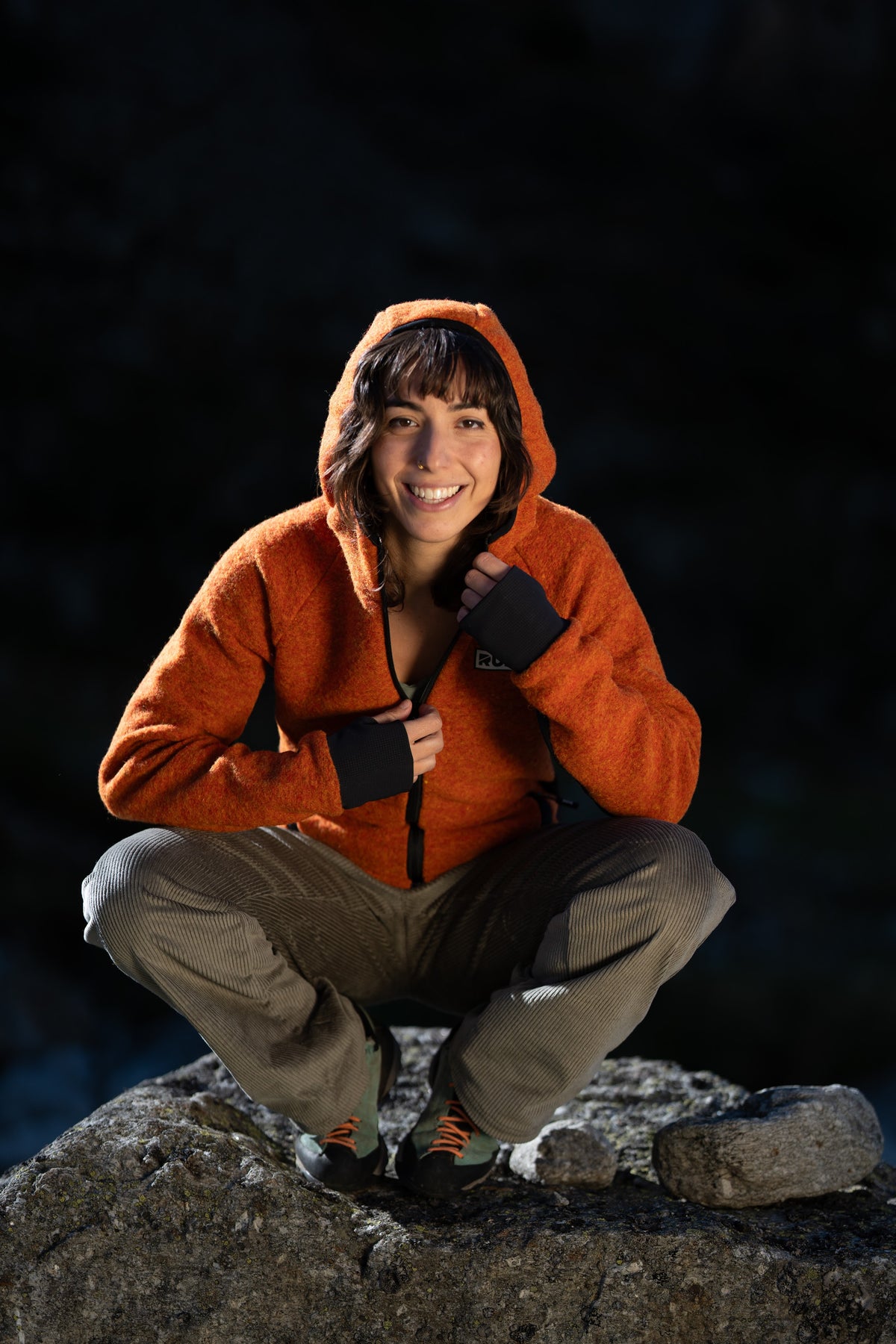 FW26-107 Peak Copper + RILA Old Green (donna accovacciata sul masso, cappuccio)